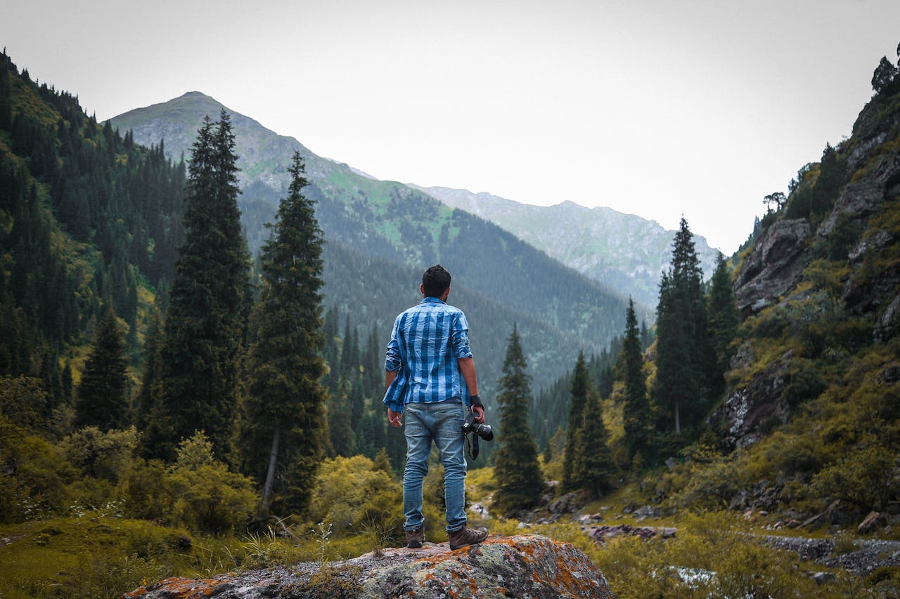 A photographer stands amidst the serene mountain landscape in Ak-Talaa, Kyrgyzstan.